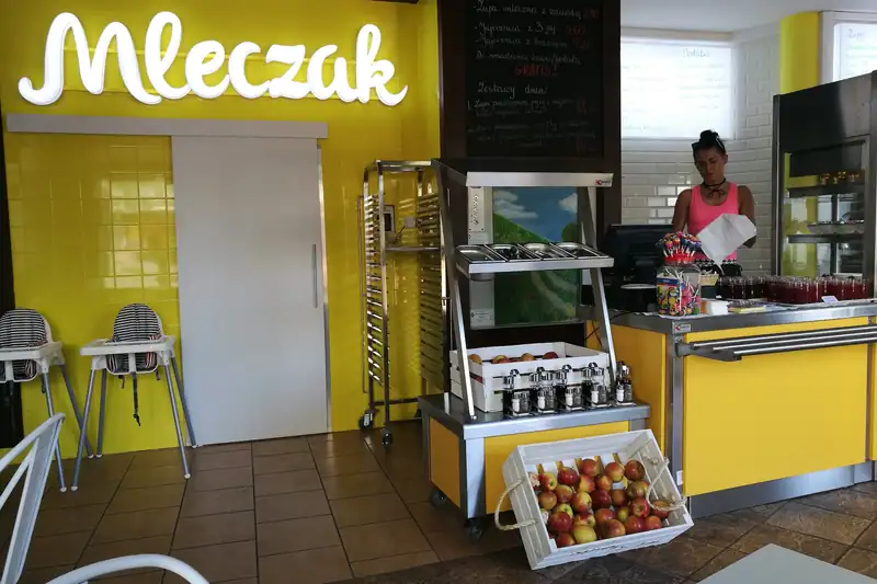 Lada wydawcza przy żółtej ścianie z logo Mleczak
